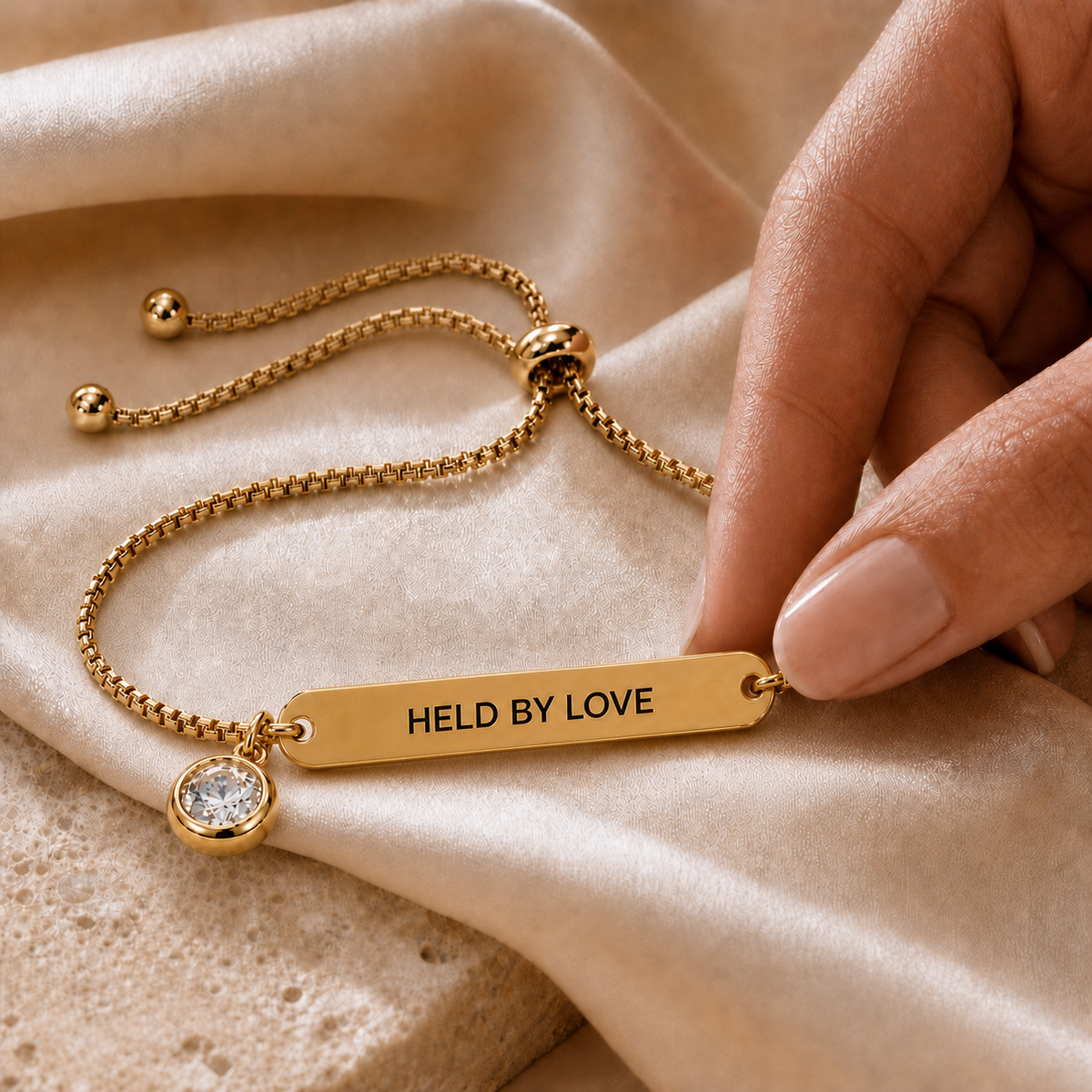 Gold-color DAYMERIT bracelet flipped to show HELD BY LOVE