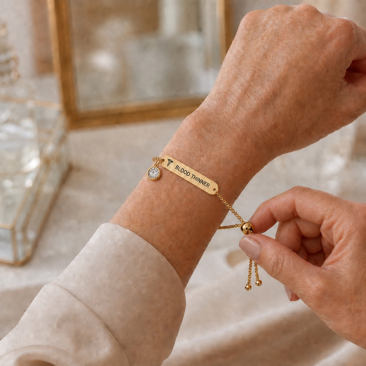 Gold-color DAYMERIT bracelet being adjusted with one hand